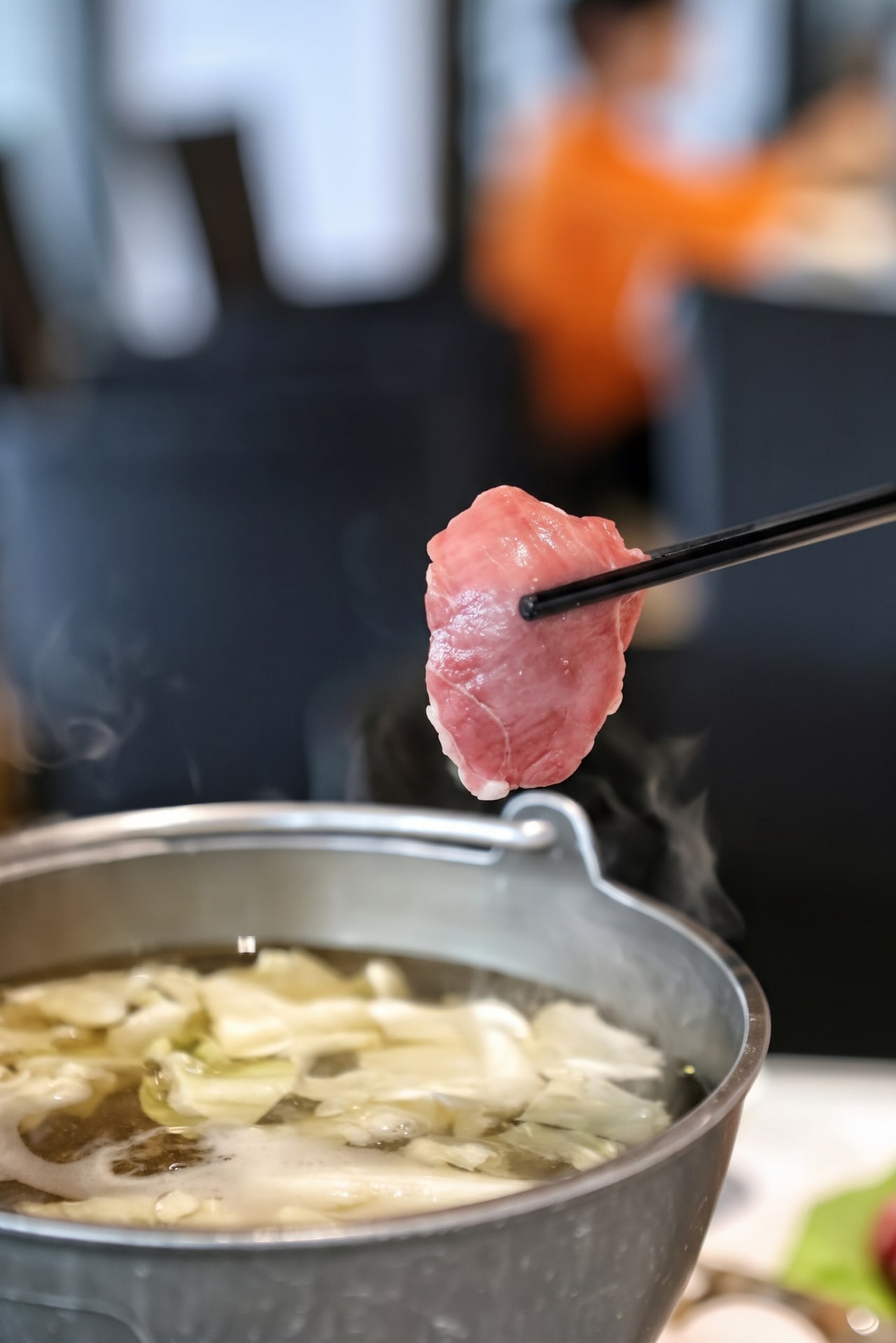 野牛火鍋，筷子夾起牛肉，搭配冒著熱氣的鍋物