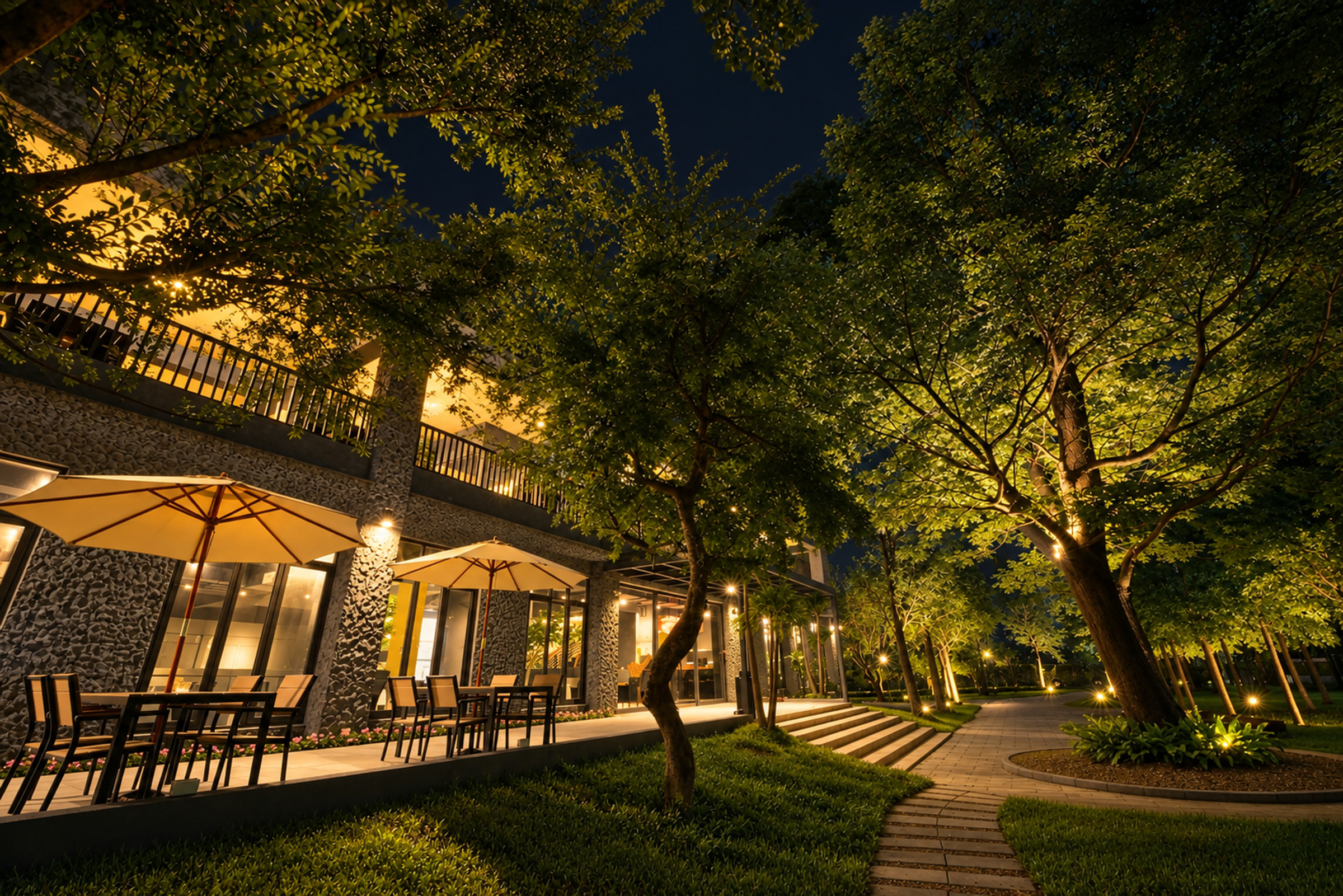 家園夜晚的庭園，樹上打著燈，步道通往餐廳